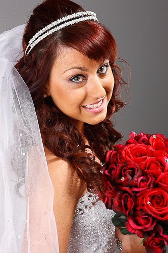 Bride in tiara with rose bouquet against studio backdrop